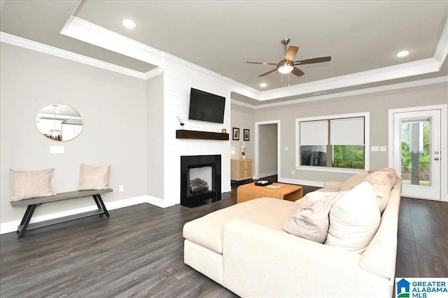 living room featuring baseboards, dark wood finished floors, a tray ceiling, recessed lighting, and a fireplace