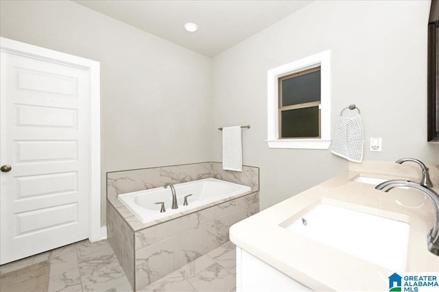 full bathroom featuring double vanity, marble finish floor, a garden tub, and a sink