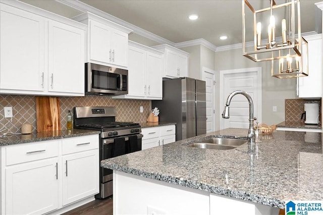 kitchen featuring ornamental molding, a sink, white cabinetry, stainless steel appliances, and dark stone counters