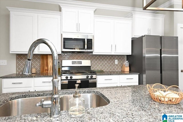 kitchen featuring dark stone countertops, stainless steel appliances, tasteful backsplash, and white cabinets