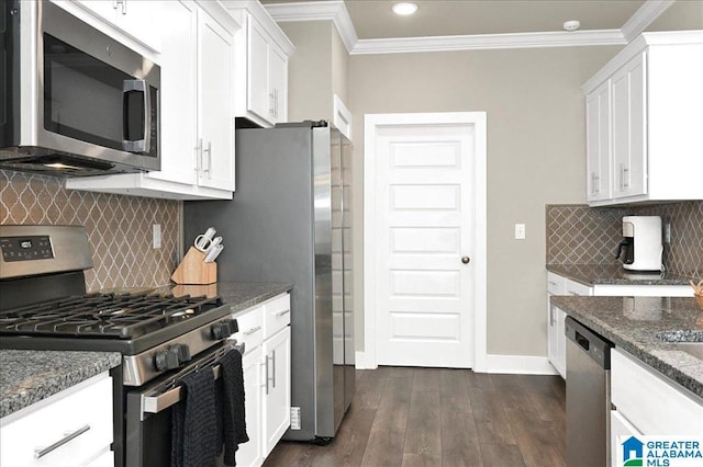 kitchen with dark stone countertops, dark wood-style floors, stainless steel appliances, white cabinets, and crown molding