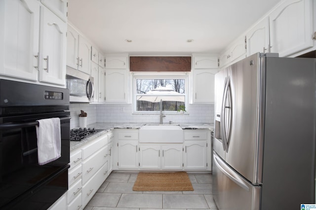 kitchen with a sink, decorative backsplash, appliances with stainless steel finishes, and white cabinetry