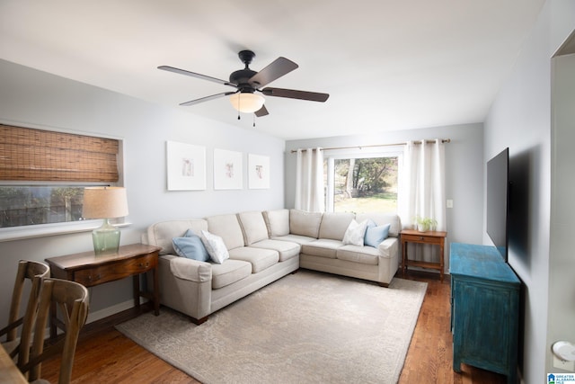 living area with baseboards, wood finished floors, and ceiling fan