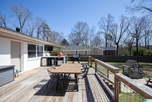 wooden terrace featuring outdoor dining area, a grill, and fence