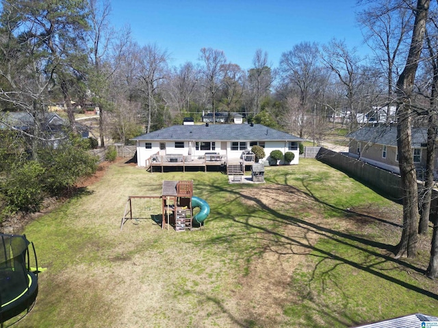 exterior space featuring a wooden deck, a fenced backyard, a playground, a trampoline, and a lawn