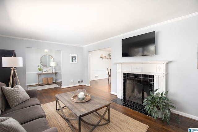 living area featuring visible vents, wood finished floors, and ornamental molding