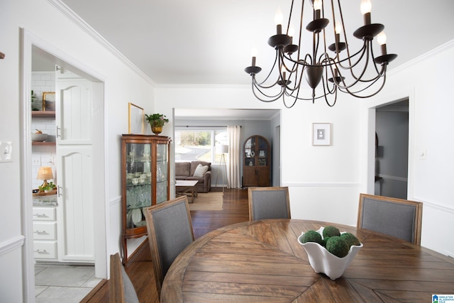 dining room with a chandelier, light wood finished floors, and ornamental molding