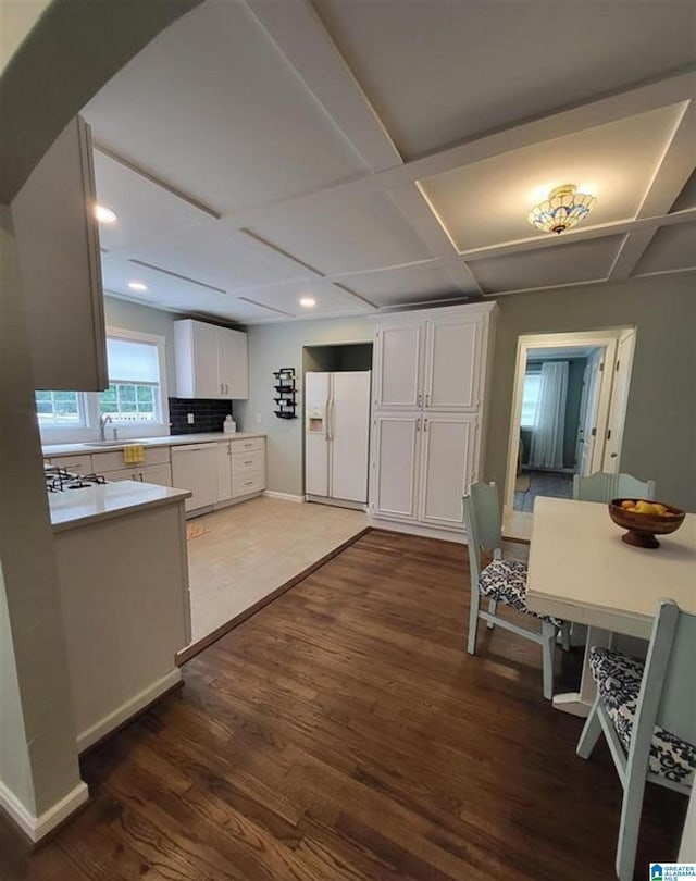 kitchen with dark wood finished floors, light countertops, white fridge with ice dispenser, white cabinets, and coffered ceiling