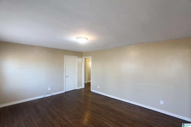 spare room with dark wood-type flooring and baseboards