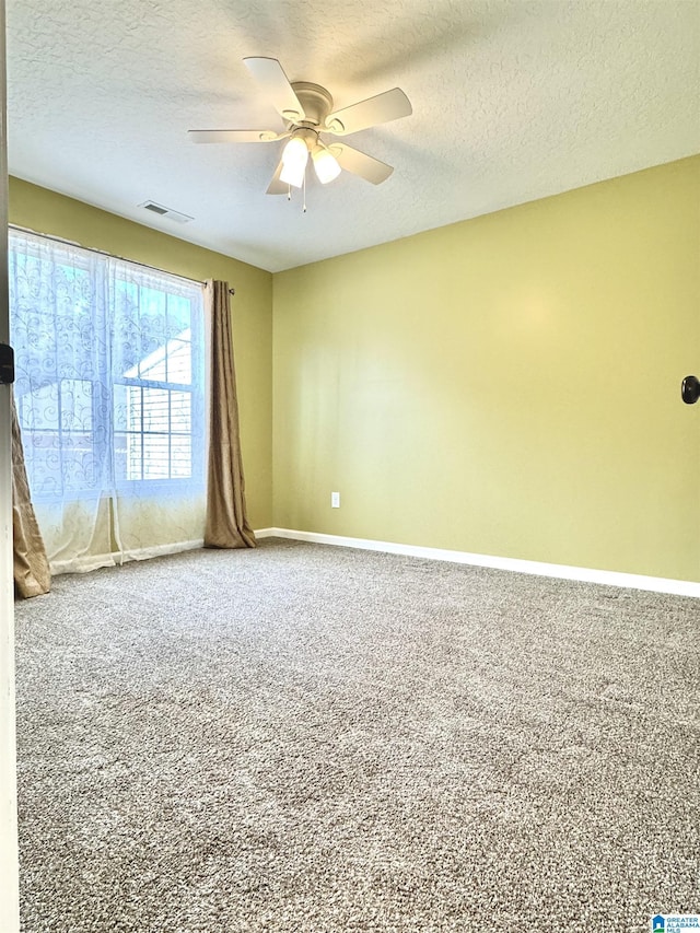 carpeted empty room with visible vents, baseboards, a textured ceiling, and a ceiling fan