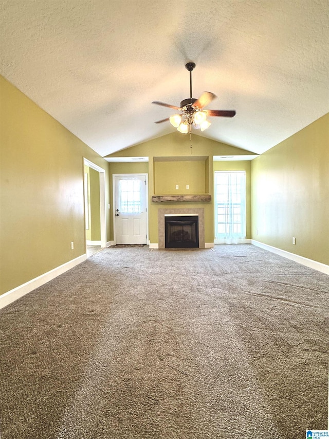 unfurnished living room featuring baseboards, carpet floors, ceiling fan, vaulted ceiling, and a tiled fireplace