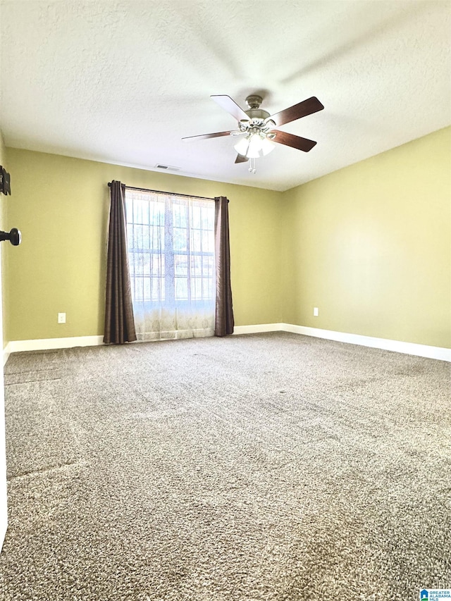 empty room featuring carpet flooring, visible vents, baseboards, and ceiling fan