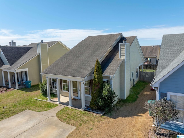 view of side of home with a yard, fence, roof with shingles, and a patio area