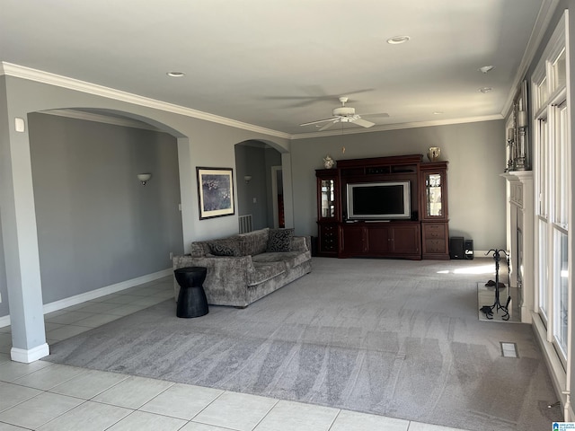 living room with arched walkways, light tile patterned floors, light carpet, and crown molding