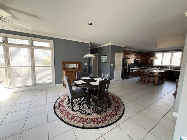 dining space with light tile patterned flooring, crown molding, and baseboards