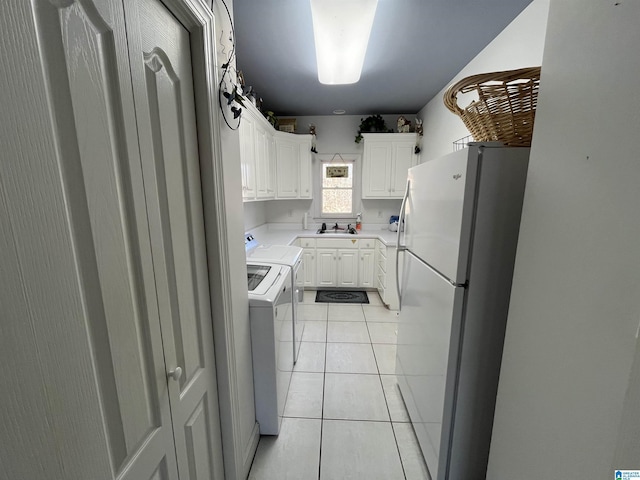 kitchen with light countertops, light tile patterned floors, white cabinets, freestanding refrigerator, and washer and dryer