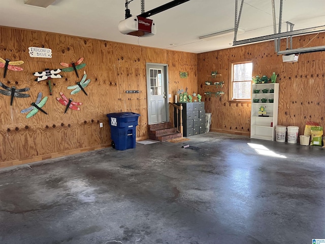 garage with wooden walls, a garage door opener, and baseboards