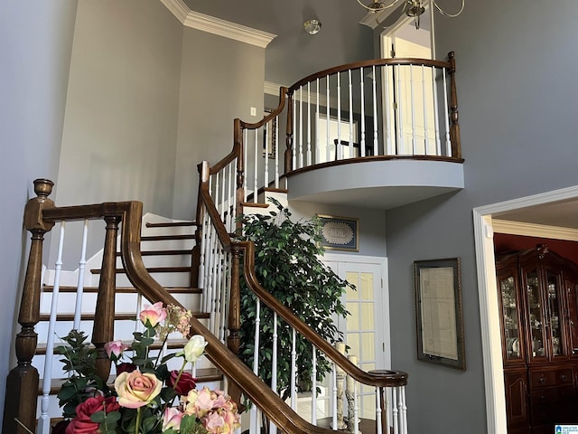 stairway with crown molding and a towering ceiling