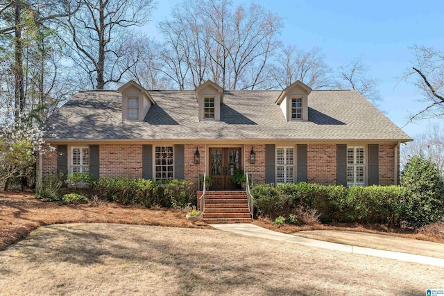 cape cod house with brick siding, french doors, and a shingled roof