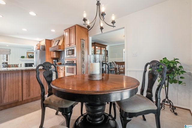 dining room featuring a chandelier, recessed lighting, wainscoting, and a decorative wall