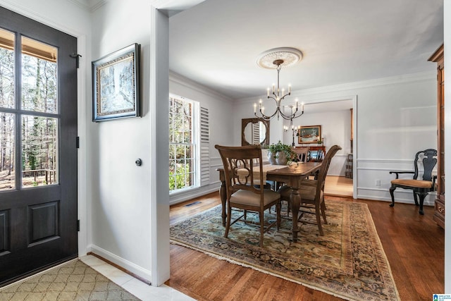 dining space featuring crown molding, wood finished floors, a healthy amount of sunlight, and visible vents