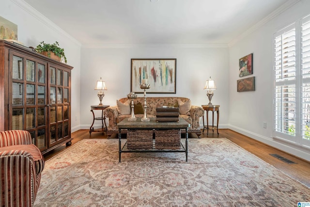 living area featuring visible vents, ornamental molding, baseboards, and wood finished floors