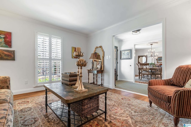 living room with a notable chandelier, wood finished floors, baseboards, and ornamental molding