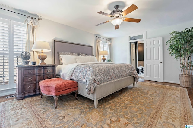 bedroom featuring visible vents, wood finished floors, baseboards, and ceiling fan