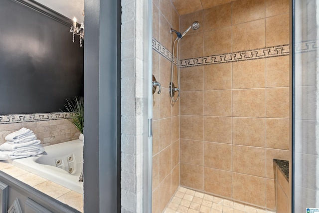 bathroom featuring a stall shower, a jetted tub, and an inviting chandelier