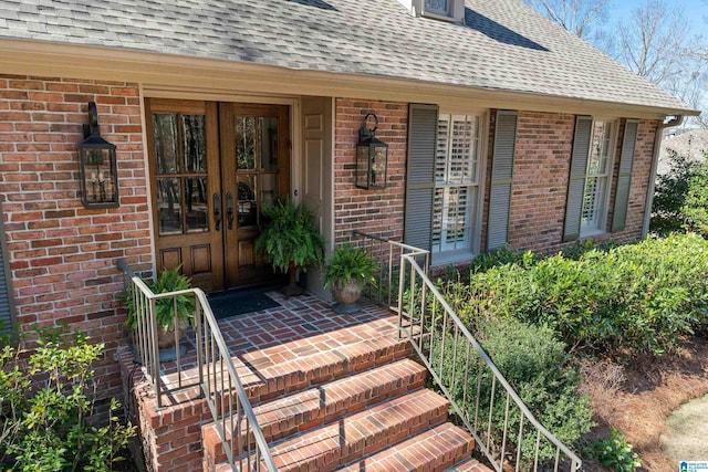 property entrance featuring brick siding, french doors, and roof with shingles