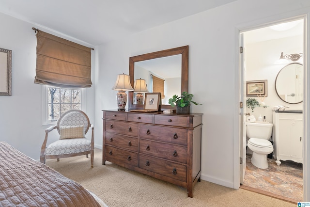 bedroom with light carpet, ensuite bathroom, and baseboards