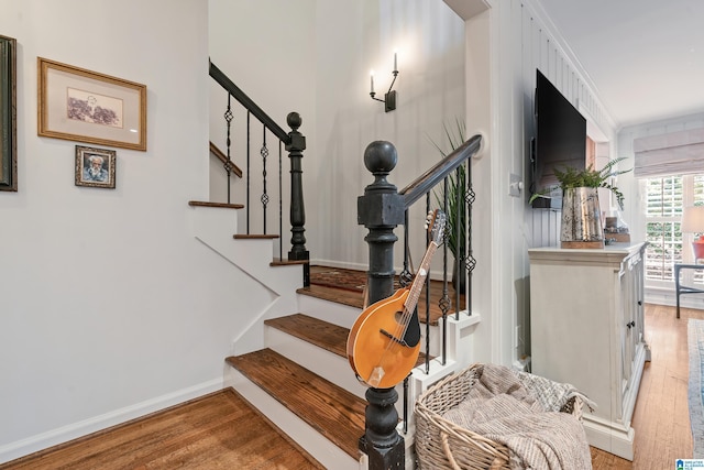 staircase featuring wood finished floors and baseboards