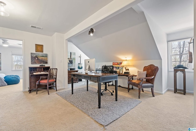 carpeted office space with a wealth of natural light, visible vents, baseboards, and vaulted ceiling