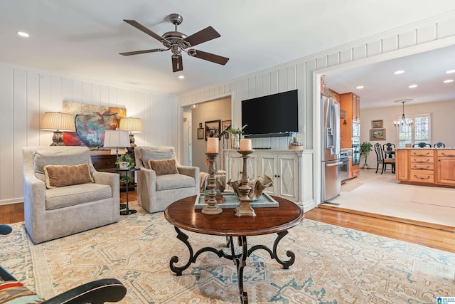 living area featuring recessed lighting, ceiling fan with notable chandelier, and light wood finished floors