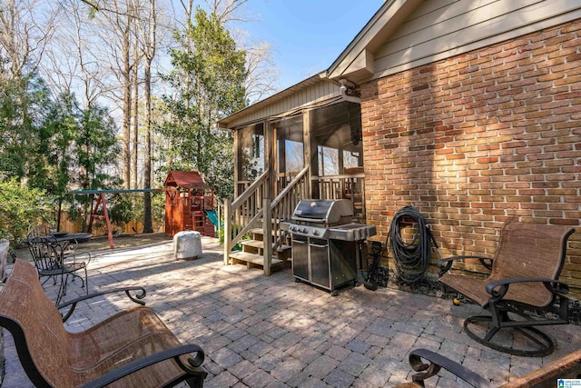 view of patio / terrace featuring grilling area, a sunroom, and a playground