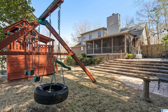 exterior space featuring a patio, fence, a sunroom, a chimney, and a playground