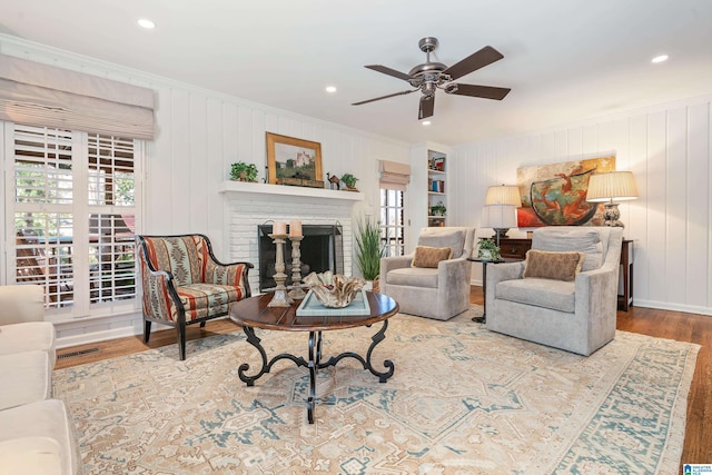 living room featuring plenty of natural light, ornamental molding, visible vents, and wood finished floors