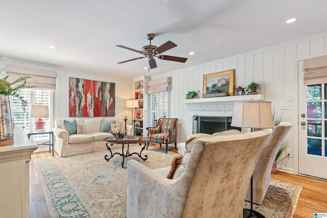 living area with a brick fireplace, wood finished floors, ornamental molding, and a healthy amount of sunlight