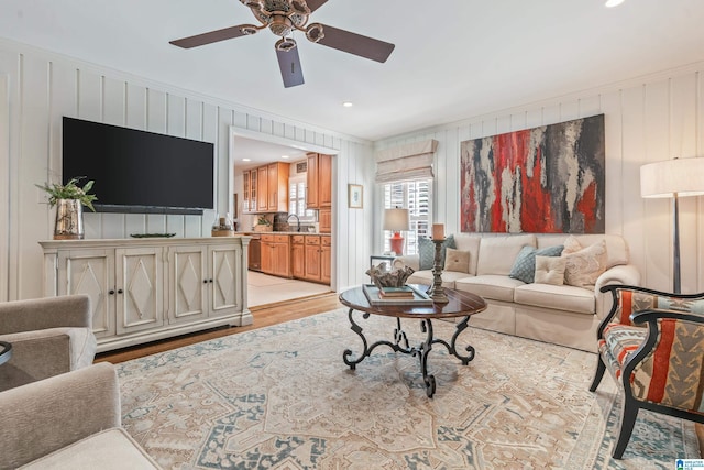 living room with light wood-type flooring, ceiling fan, and ornamental molding