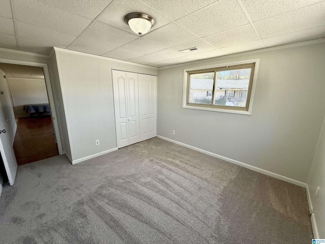 unfurnished bedroom featuring a paneled ceiling, baseboards, carpet floors, and visible vents