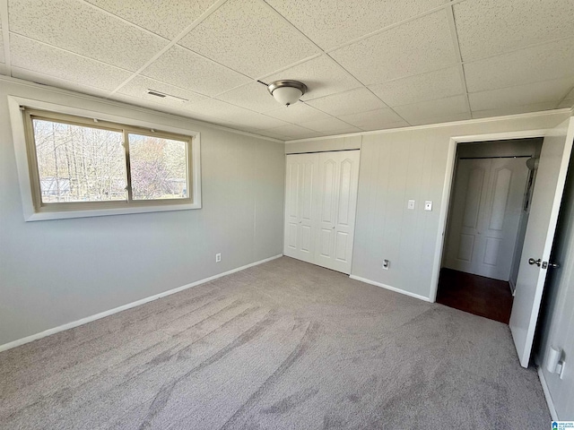 unfurnished bedroom with a closet, a paneled ceiling, and carpet flooring