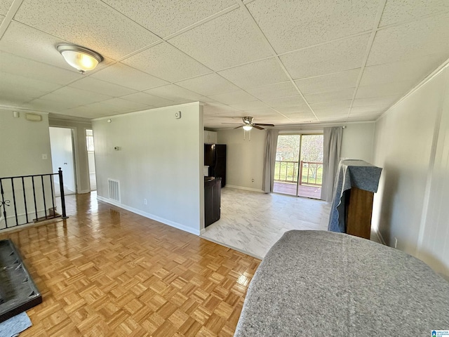 living room featuring visible vents, ornamental molding, baseboards, and a drop ceiling