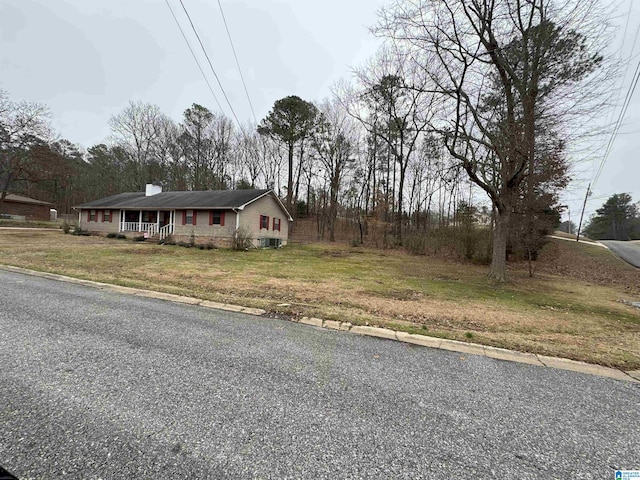 view of front of house with a porch, a chimney, and a front lawn