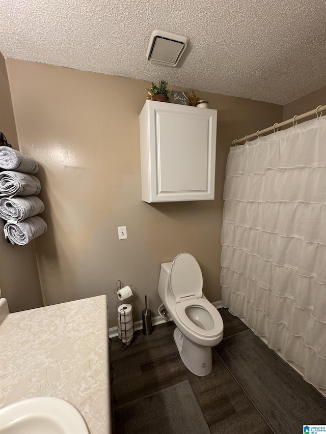 bathroom with a shower with shower curtain, baseboards, visible vents, a textured ceiling, and toilet