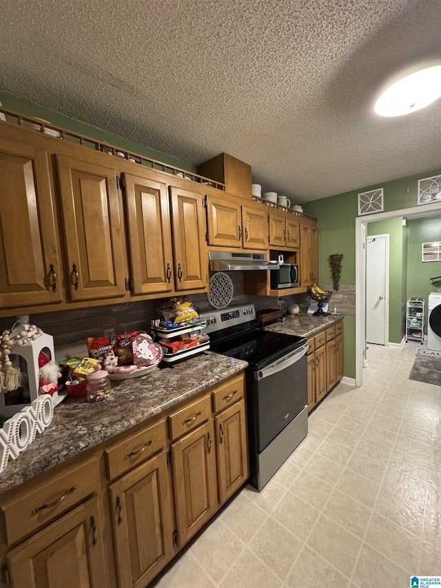 kitchen featuring under cabinet range hood, brown cabinets, appliances with stainless steel finishes, and a textured ceiling