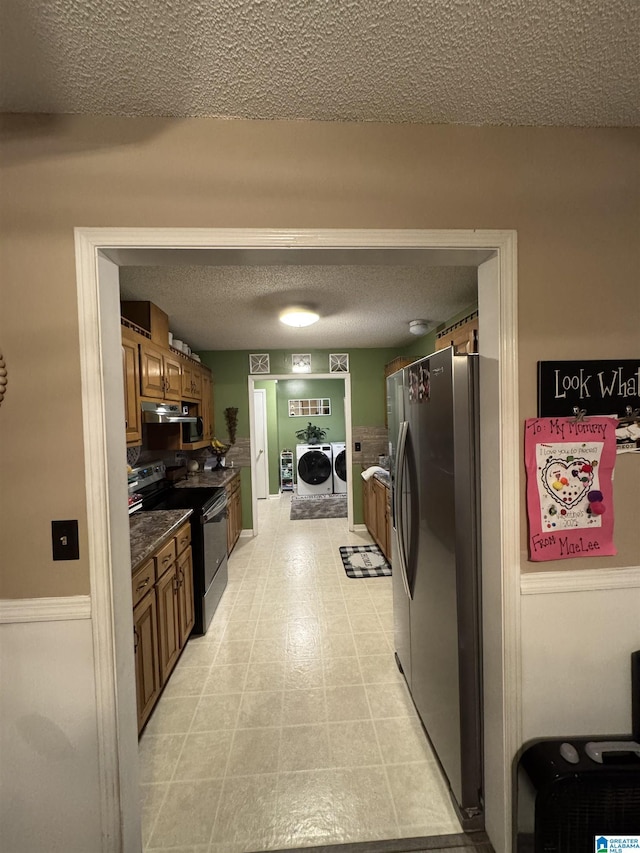 kitchen featuring stainless steel fridge with ice dispenser, washing machine and dryer, electric range oven, brown cabinets, and a textured ceiling