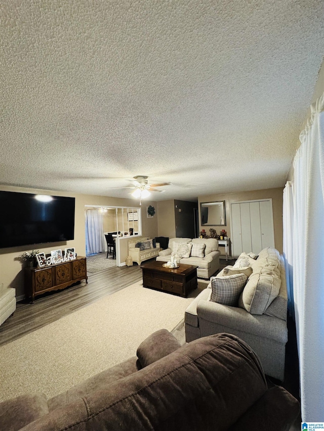 living area with a textured ceiling, wood finished floors, and ceiling fan