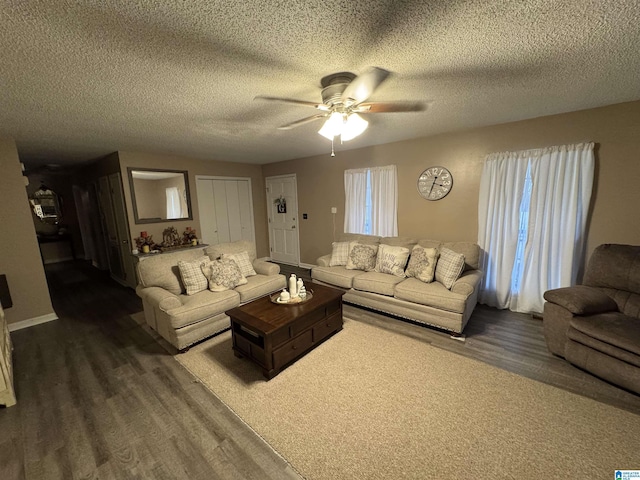 living room with dark wood-type flooring, a ceiling fan, and a textured ceiling