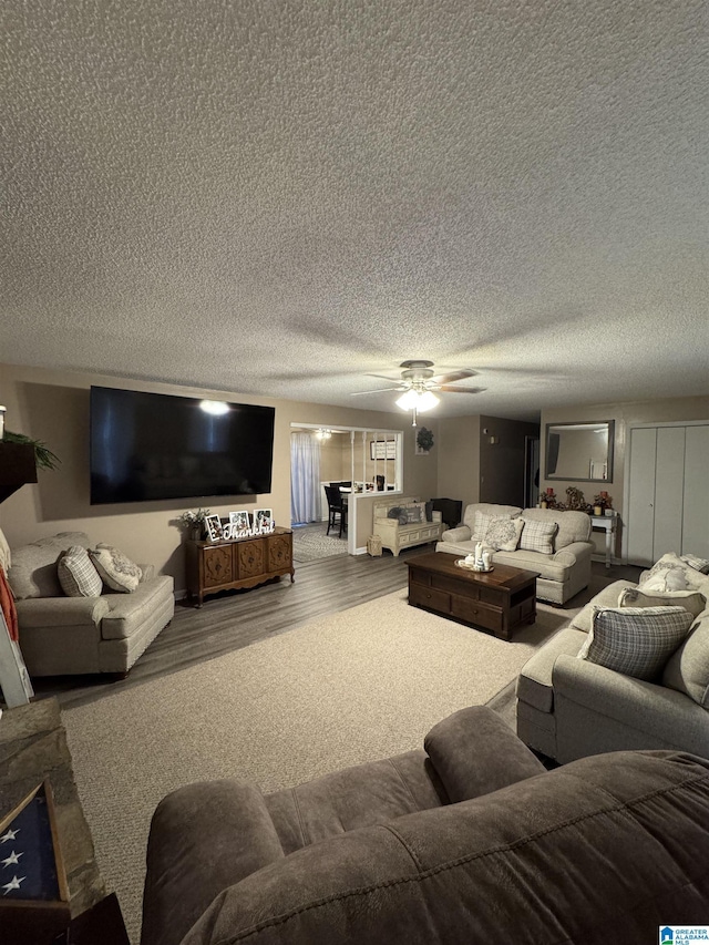 living room featuring a textured ceiling, ceiling fan, and wood finished floors