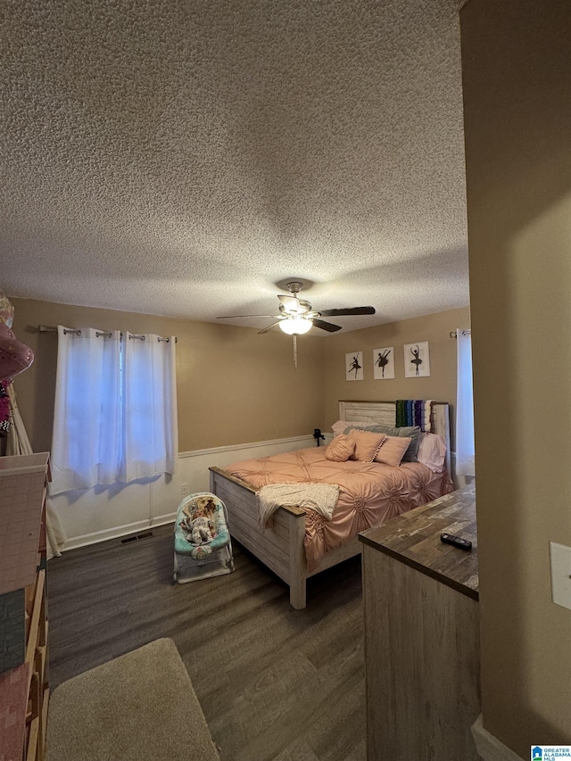 bedroom featuring wood finished floors, a ceiling fan, visible vents, and a textured ceiling